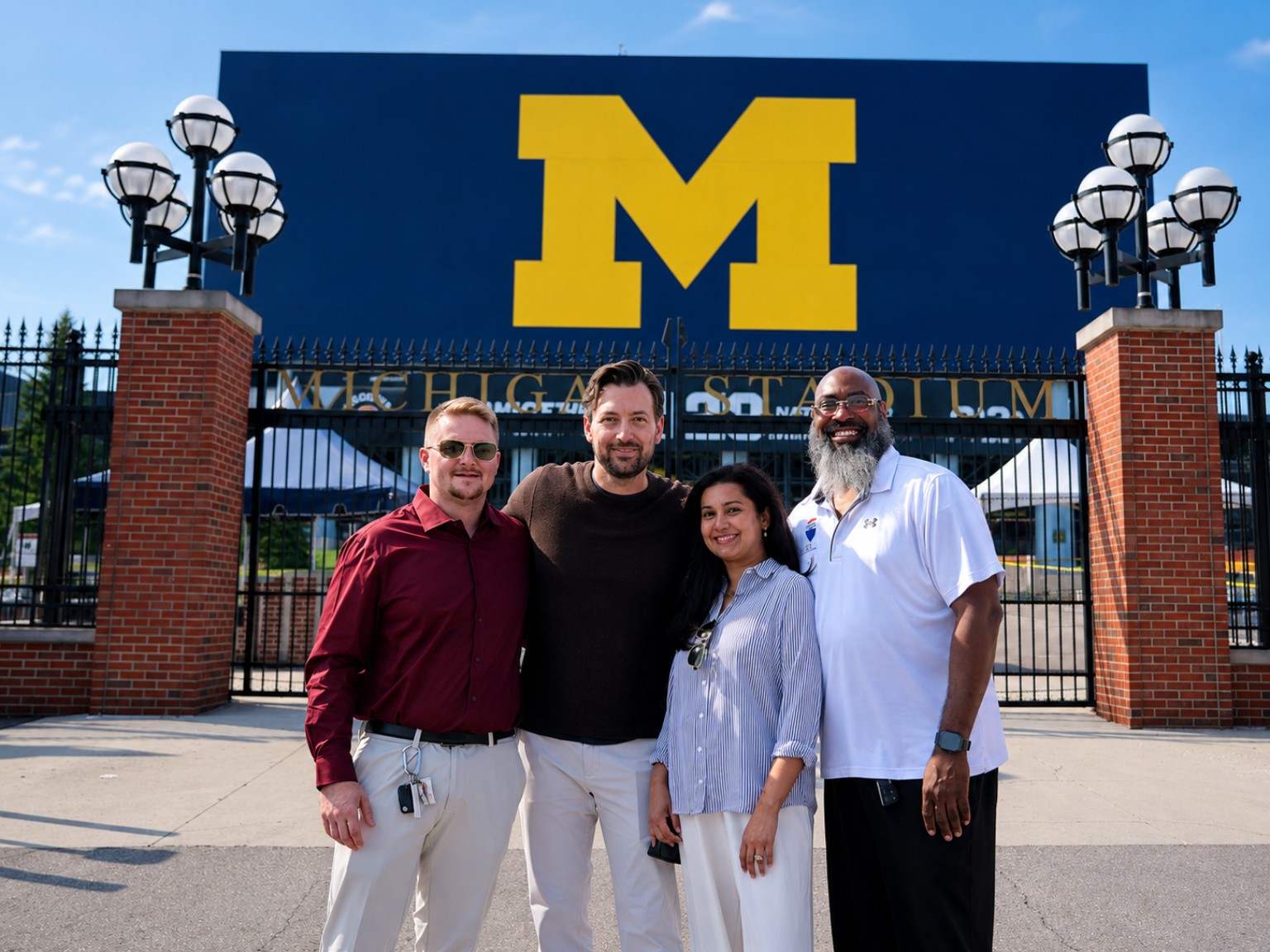 Four RE/MAX Platinum team members in front of Michigan Stadium in Ann Arbor
